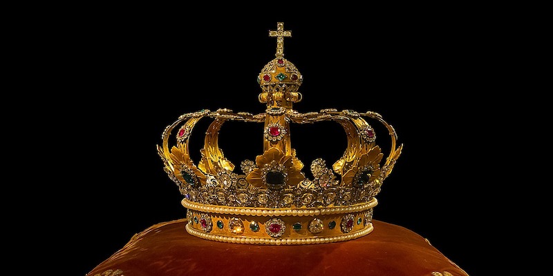 gold-crown-on-red-cushion-with-black-background