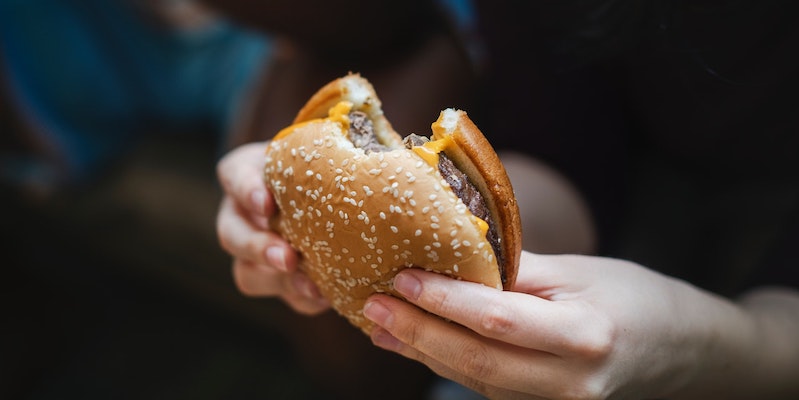 woman-holding-a-cheeseburger-with-a-bite-in-it