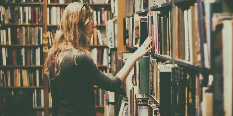 woman-looking-through-books-on-a-book-shelf-in-a-library