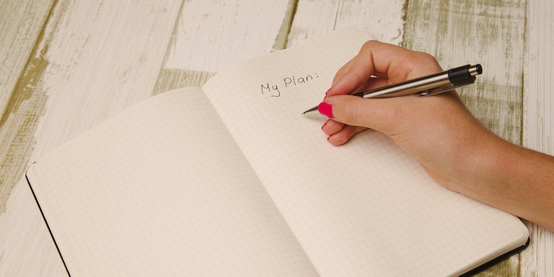 woman-with-pink-nails-writing-plan-in-her-journal-with-pen